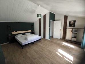 Ein Schlafzimmer mit Bett, Nachttischen, einer Pendelleuchte, einer Tür und einem Bild an der Wand.