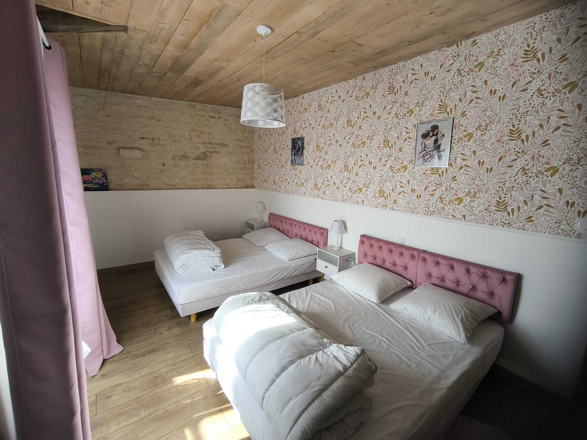 Ein Schlafzimmer mit zwei Betten, Holzboden, einer Wand mit Muster und einer Hängelampe.