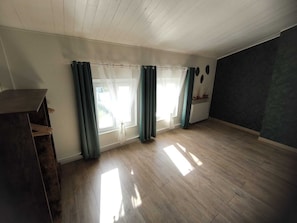 A room with wooden flooring, a dark-colored piano, and a large window with curtains. - Family home in the Poitevin Marshes (Saint-Sigismond)