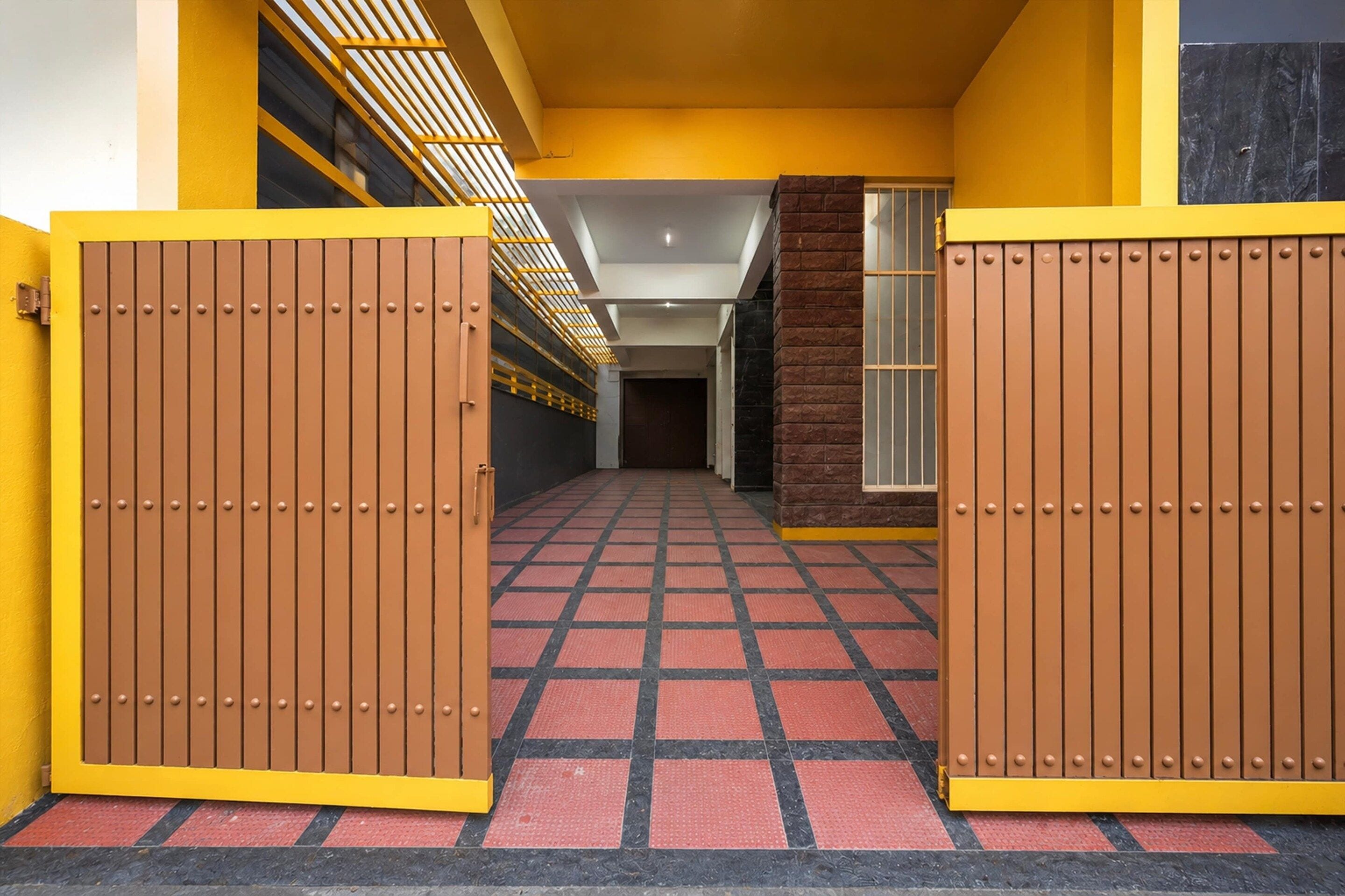 A hallway with a checkered floor, yellow walls, and brown doors.