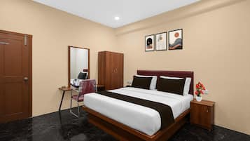 A hotel room with a bed, a desk, a chair, a wardrobe, and artwork on the wall.