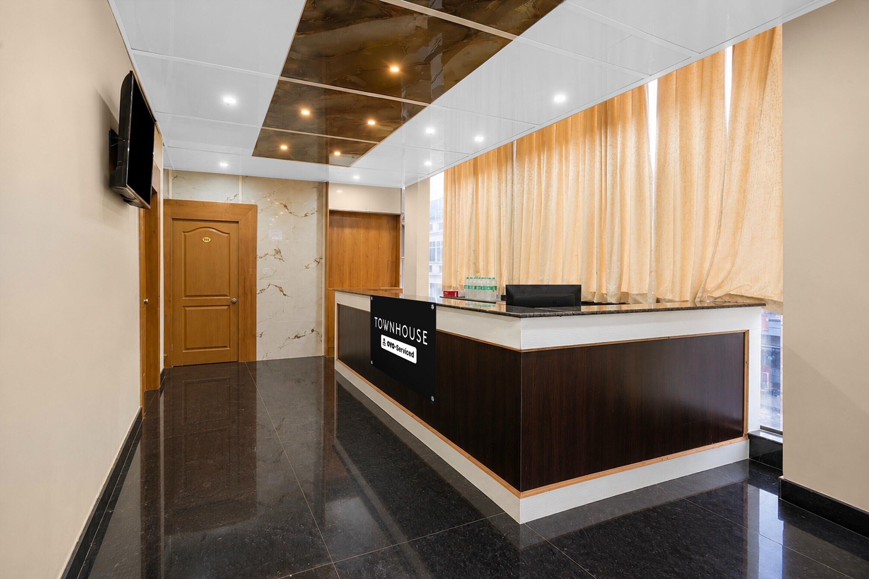 A reception area with a marble wall, a wooden door, and a counter with a sign.
