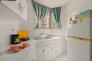 Eine kleine Küche mit Spüle, Kaffeemaschine, Toaster und Kühlschrank.