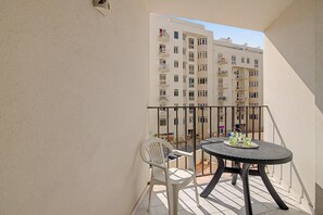 A balcony with a round table and two chairs, overlooking a street with buildings. - Apartment 'Gabriel 1' with Shared Pool and Balcony (Armação de Pêra)