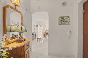 A hallway with a wooden dresser, a mirror, a lamp, and a painting on the wall. - Apartment 'Gabriel 1' with Shared Pool and Balcony (Armação de Pêra)