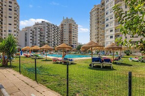 A pool area with sun loungers and umbrellas, surrounded by high-rise buildings. - Apartment 'Gabriel 1' with Shared Pool and Balcony (Armação de Pêra)