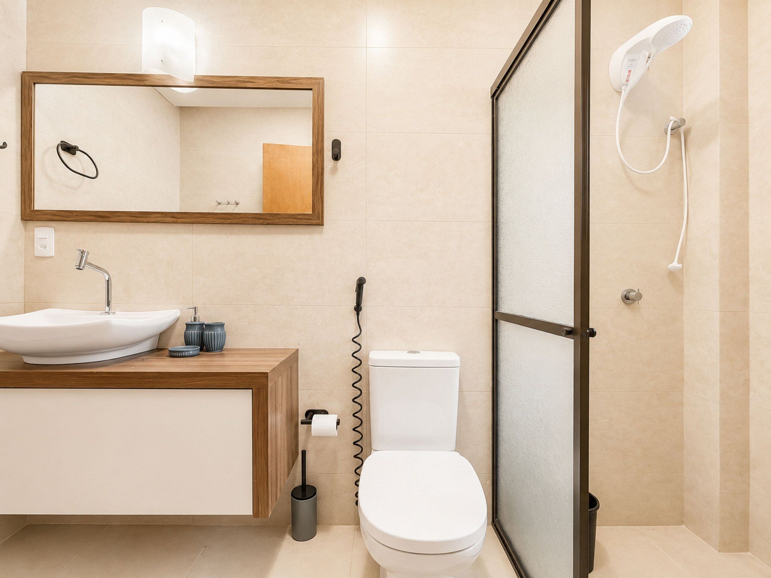 Une salle de bain moderne avec un meuble-lavabo en bois, un lavabo blanc, des toilettes et une douche séparée par une paroi de verre.