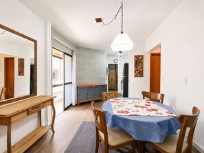 A dining area with a round table, chairs, and a hanging light fixture. - Residencial Itaguaçu by LikeHome (Bombinhas)