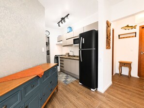 Une cuisine de taille réduite, avec un réfrigérateur noir, un four à micro-ondes et une cuisinière.