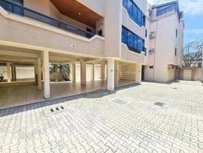 A covered outdoor area with a tiled floor, columns, and a palm tree. - Residencial Itaguaçu by LikeHome (Bombinhas)