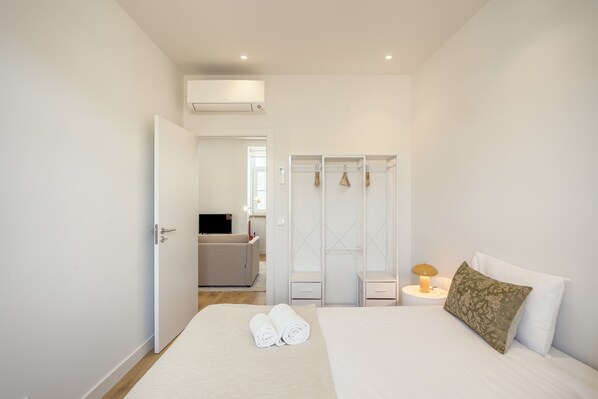 Habitación de hotel con cama, armario, escritorio y televisor.