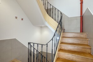 Una escalera con escalones de madera y barandas de metal negro, que conduce a una plataforma con una tubería roja.