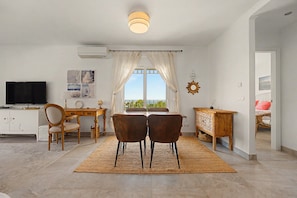 A modern living room with a dining area, a TV, and a view of the outdoors. - Apartment 'Casa Luz' with Sea Views (Benalmádena)