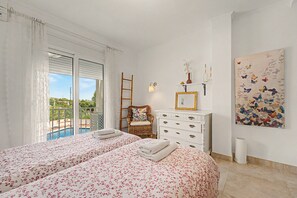 A bedroom with two beds, a dresser, a painting, and a view of a pool. - Apartment 'Casa Luz' with Sea Views (Benalmádena)