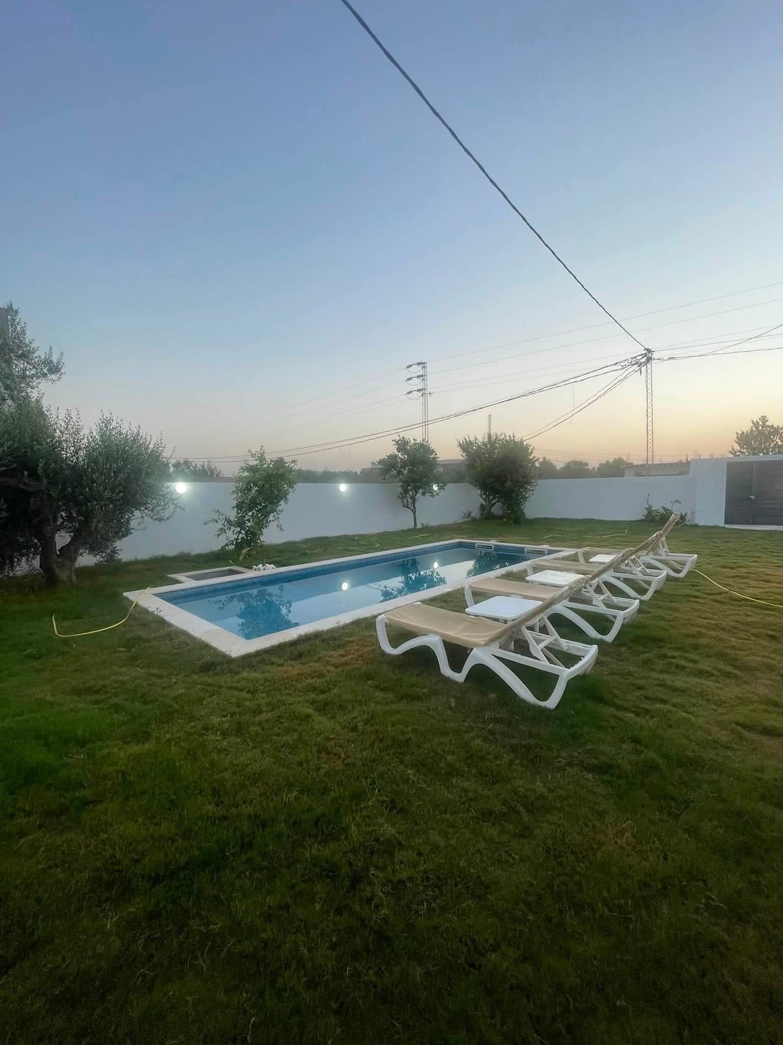 Piscina con sillas de descanso y césped.
