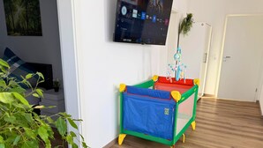Una habitación con televisión montada en la pared, una alberca para bebés y una puerta.