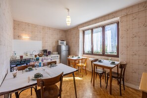 A dining area with a table set for four, a refrigerator, and a microwave. - Bellevue Guest Rooms - Room 3 (Junhac)