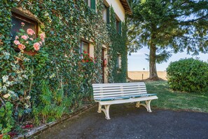 A bench outside a building with a garden wall covered in ivy and flowers.