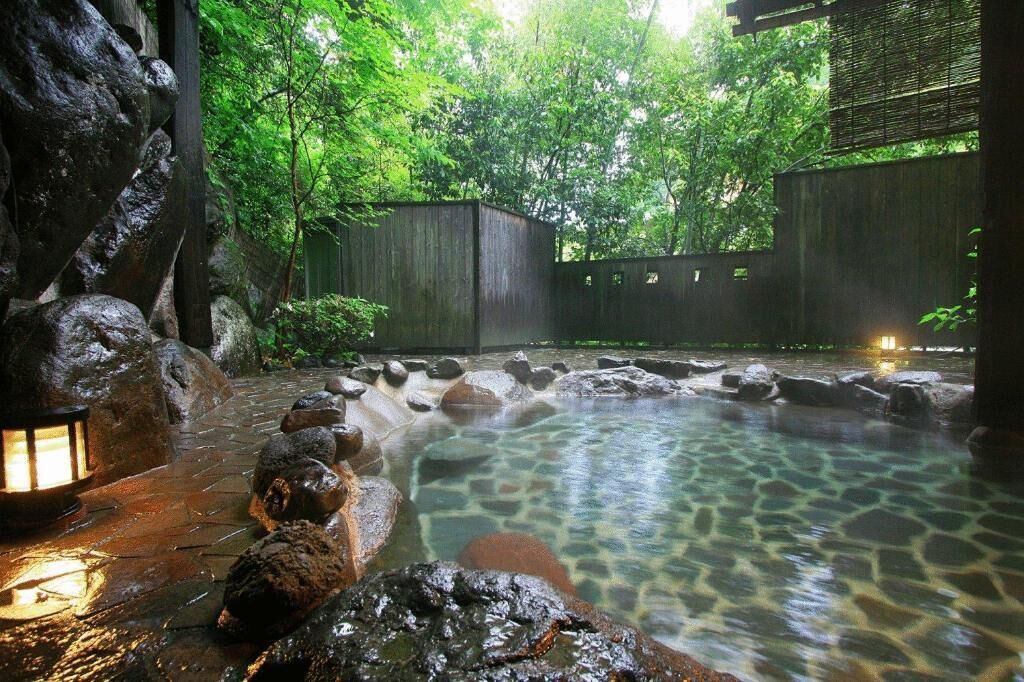 A hot spring area with a stone pathway, rocks, and a wooden fence.