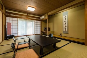 A traditional Japanese room with tatami flooring, a low table, and a sliding door. - Hakone Shiunso (Hakone)