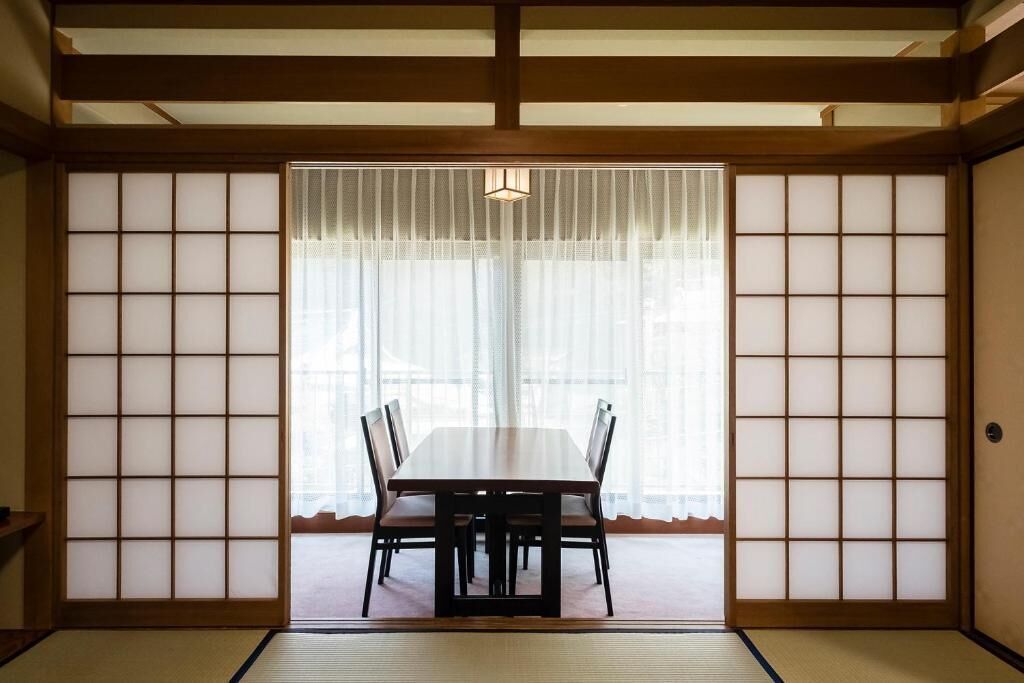 A traditional Japanese room with tatami flooring, a low table with chairs, and shoji screens.