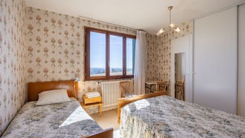 Une chambre avec deux lits, une fenêtre, un radiateur, un bureau et une chaise.