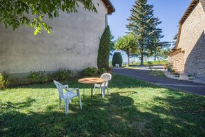 A courtyard with a stone wall, a grassy area, and a seating arrangement.