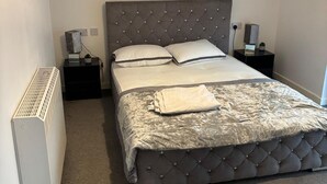 Uma cama bem arrumada com cabeceira estofada, duas almofadas e um cobertor dobrado sobre a cama.