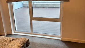 Quarto com porta de vidro deslizante que dá para uma varanda externa.