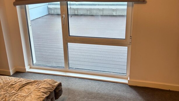 Una habitació amb una porta corredissa de vidre que dona a un balcó exterior.