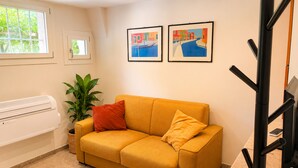 A room with a yellow sofa, a potted plant, and two framed artworks on the wall. - Dorsoduro Venice Loft by Venicescape (Venezia)