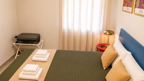 A hotel room with a bed, a suitcase on a trolley, a bedside table with a lamp, and a wall with framed artwork. - Dorsoduro Venice Loft by Venicescape (Venezia)