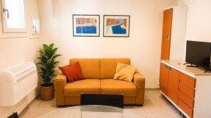A compact living space with a sofa, a television, a potted plant, and two framed artworks on the wall. - Dorsoduro Venice Loft by Venicescape (Venezia)