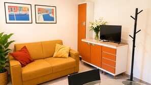 A room with a sofa, a cabinet with drawers, a television on top, and two framed pictures on the wall. - Dorsoduro Venice Loft by Venicescape (Venezia)