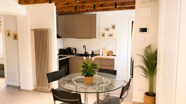 A modern kitchen with a glass dining table, chairs, and a potted plant. - Dorsoduro Venice Loft by Venicescape (Venezia)