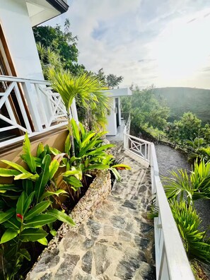 A stone staircase leading to a white building with a view of a lush landscape. - Villa Atlantide – 3 BR Hillside with Ocean View & Infinity Pool (Las Terrenas)