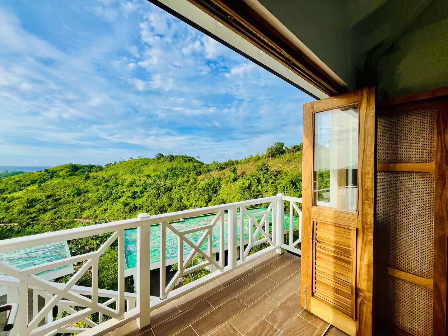 Un balcón con vistas a un paisaje verde exuberante y una piscina turquesa.