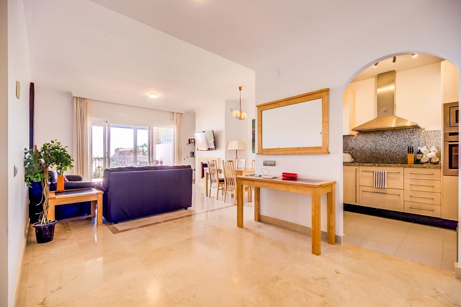 Una sala de estar moderna con sofá, una mesa de comedor y una zona de cocina con encimeras de granito.
