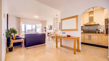 Una sala de estar moderna con sofá, una mesa de comedor y una zona de cocina con encimeras de granito.
