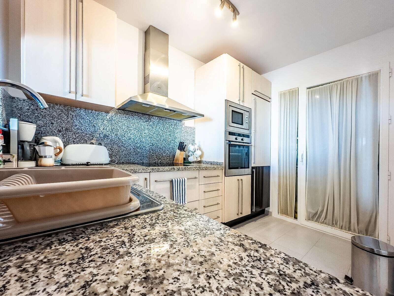 A modern kitchen with granite countertops, stainless steel appliances, and a built-in oven.