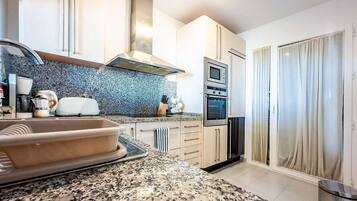 A modern kitchen with granite countertops, stainless steel appliances, and a built-in oven.