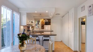 A modern kitchen with a dining area, a clock, and a view of the outside.