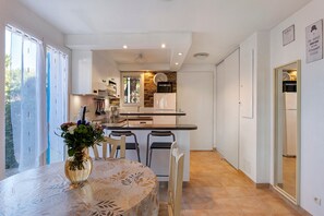 A modern kitchen with a dining area, a clock, and a view of the outside.