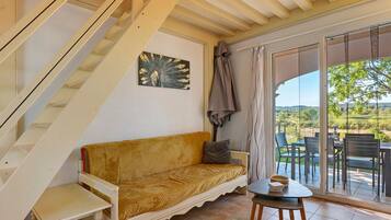 Ein Zimmer mit Treppe, einer Couch, einem kleinen Tisch und Blick ins Freie.