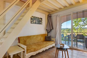 Una habitación con escalera, un sofá, una mesita y vistas al exterior.