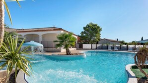 A swimming pool with a fountain, surrounded by palm trees and a fence.