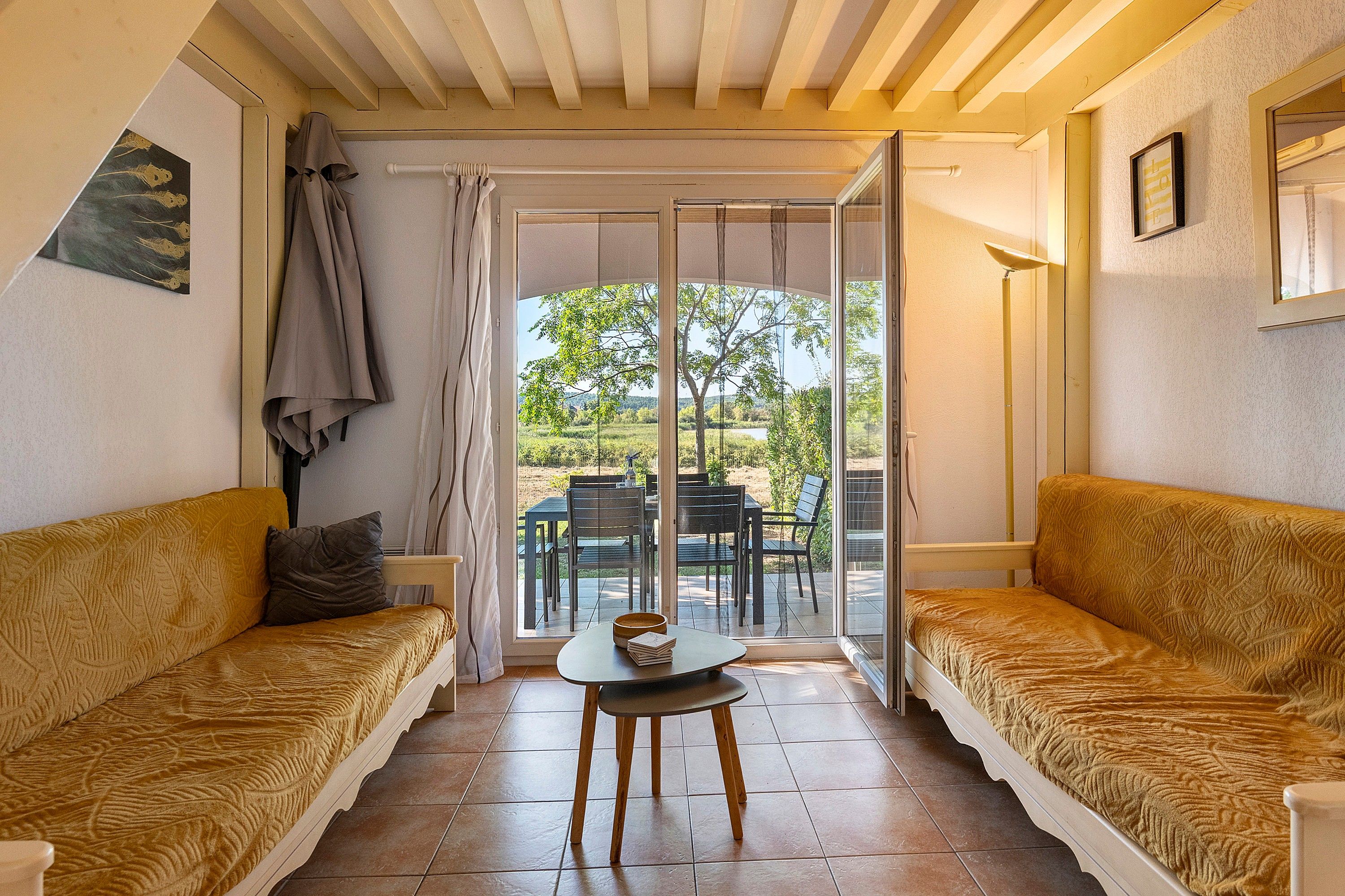 A room with two sofas facing a sliding glass door leading to an outdoor patio with a table and chairs.
