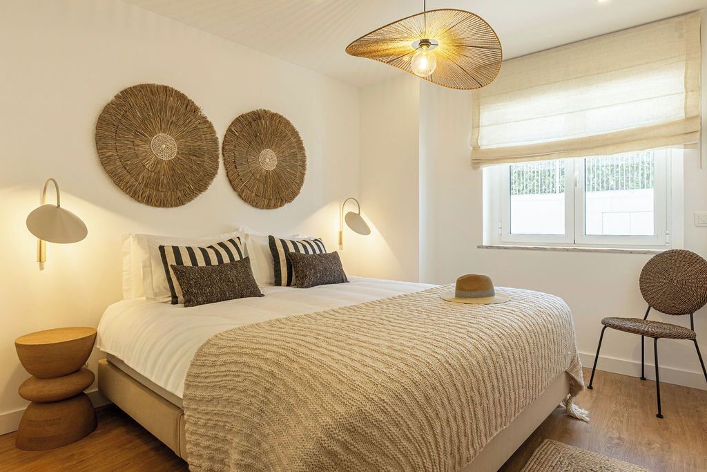 Une chambre à coucher avec un lit, des lampes de chevet, une table ronde, une chaise et une fenêtre donnant sur un beau paysage.
