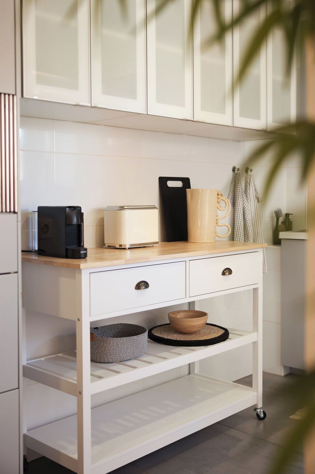 A kitchen with a white countertop, a coffee maker, a toaster, a cutting board, and a mug.