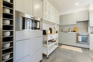 Una cocina moderna con armarios blancos, horno empotrado y microondas.